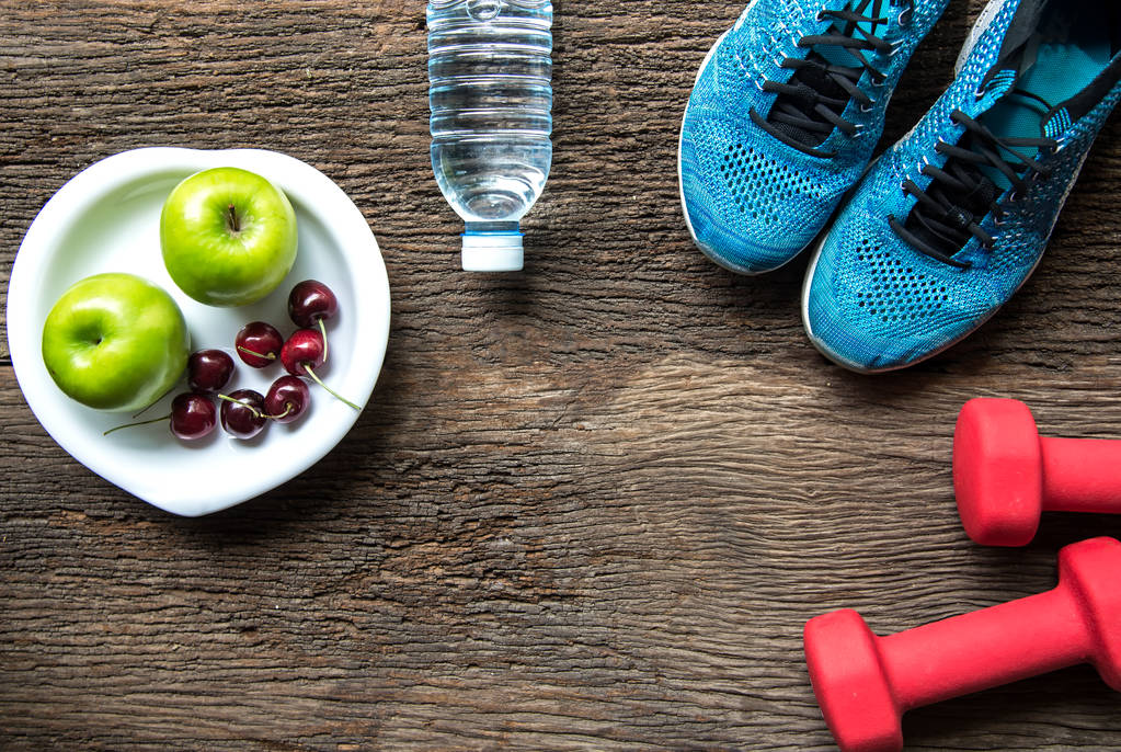 Zdrowy styl życia sport sprzęt fitness, trampki, zielone jabłuszko, świeżej wody i zdrowej żywności na stare drewniane tła. Pojęcie zdrowego. - Zdjęcie, obraz