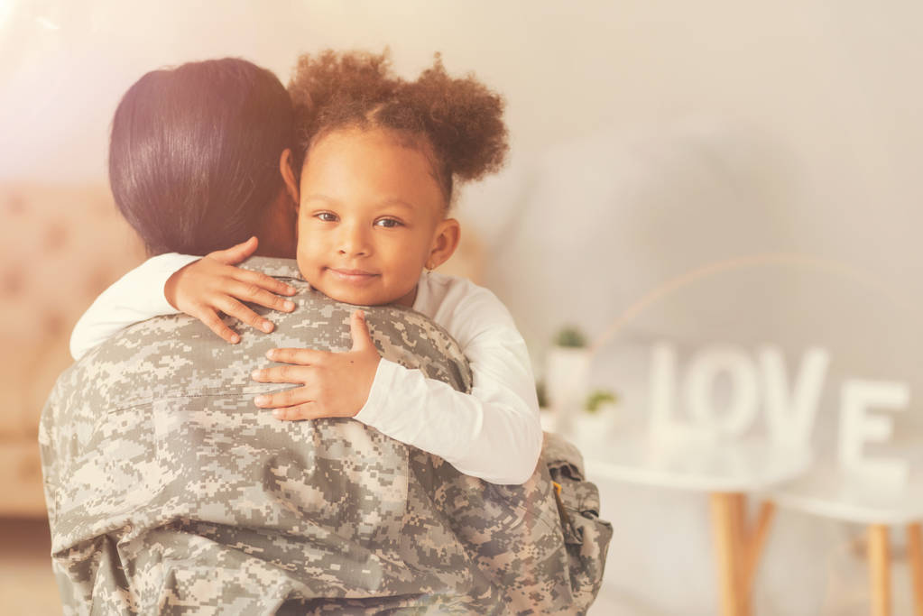 Carino ragazza riccia abbracciando sua madre in uniforme militare
 - Foto, immagini