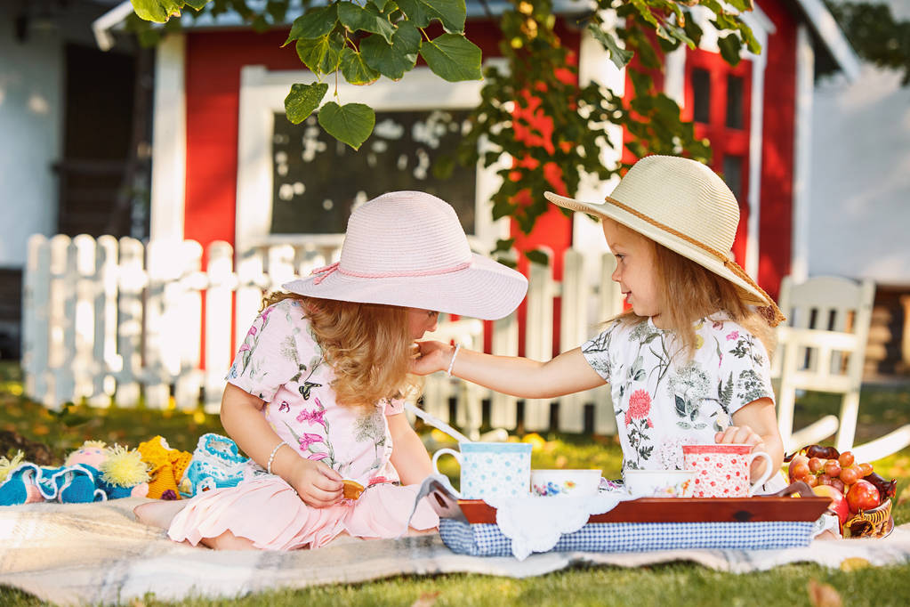 Две маленькие девочки сидят на зеленой траве
 - Фото, изображение