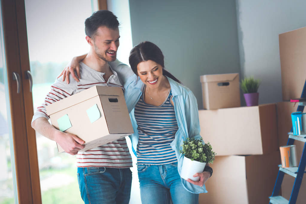 Счастливая молодая пара распаковывает коробки и переезжает в новый дом
 - Фото, изображение