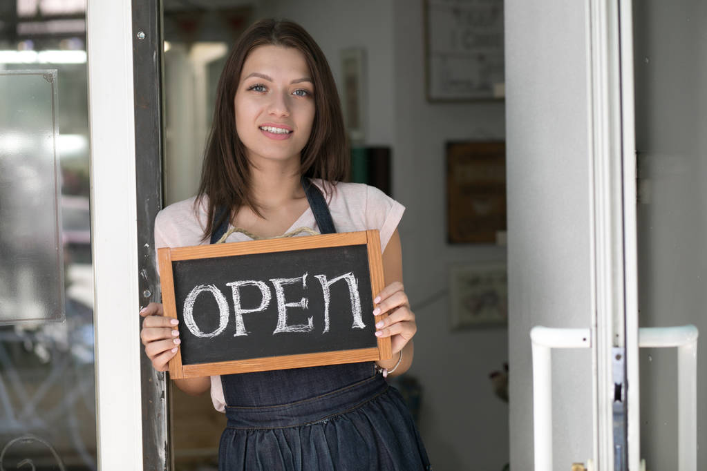 Retrato de una joven sosteniendo un letrero abierto en su tienda
 - Foto, Imagen