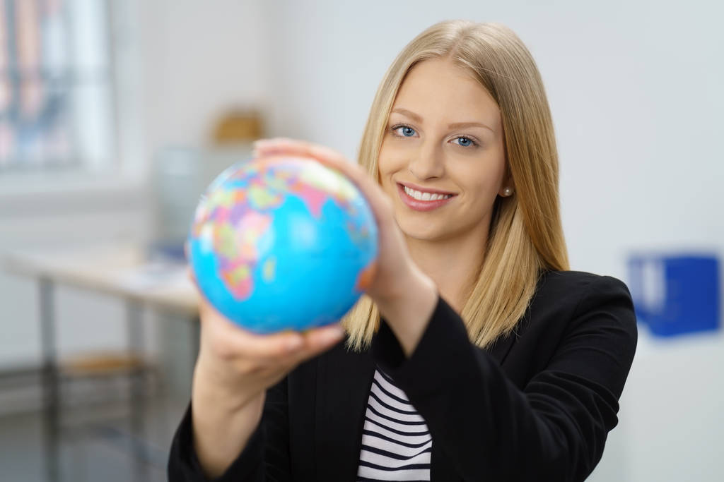 Blonde vrouw bedrijf globe glimlachen - Foto, afbeelding