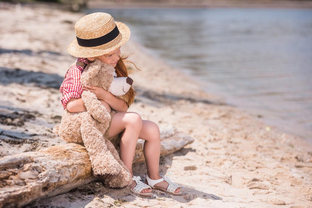 criança com ursinho de pelúcia na praia
 - Foto, Imagem