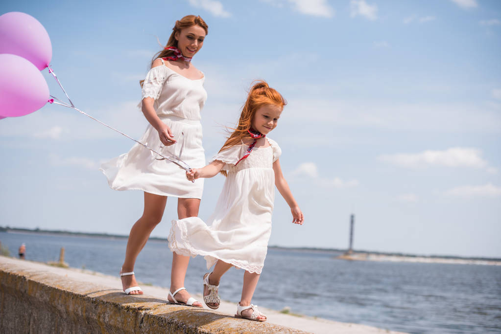 мати і дочка з повітряними кулями на березі моря
 - Фото, зображення