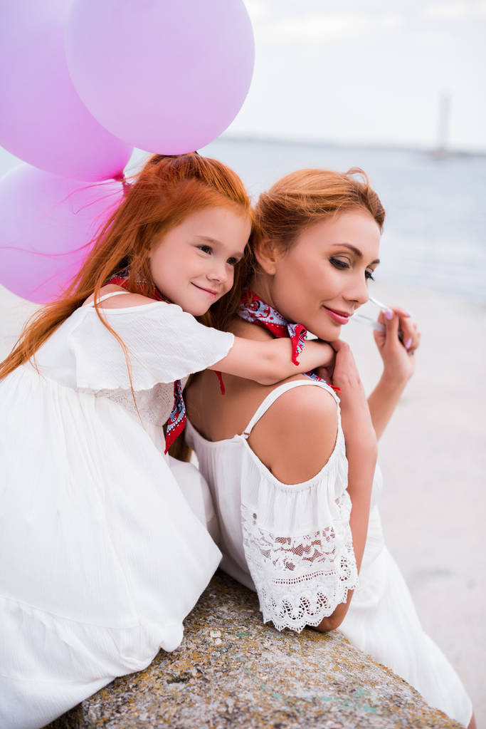 mother and daughter with balloons at seashore - Photo, Image