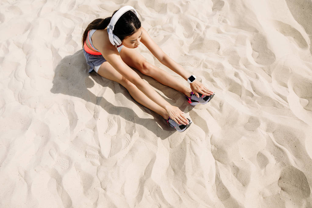 спортсменка, растянувшаяся на песке
 - Фото, изображение