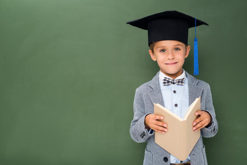 écolier en chapeau de graduation et avec livre
 - Photo, image