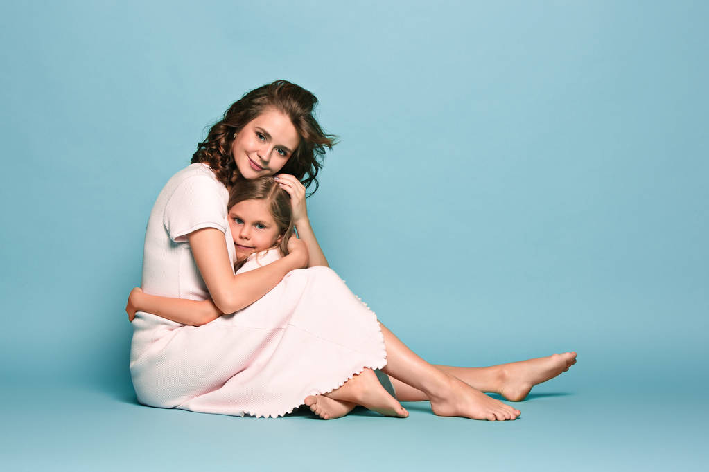Raskaana oleva äiti ja teini-ikäinen tytär. Perhe studio muotokuva sininen tausta
 - Valokuva, kuva
