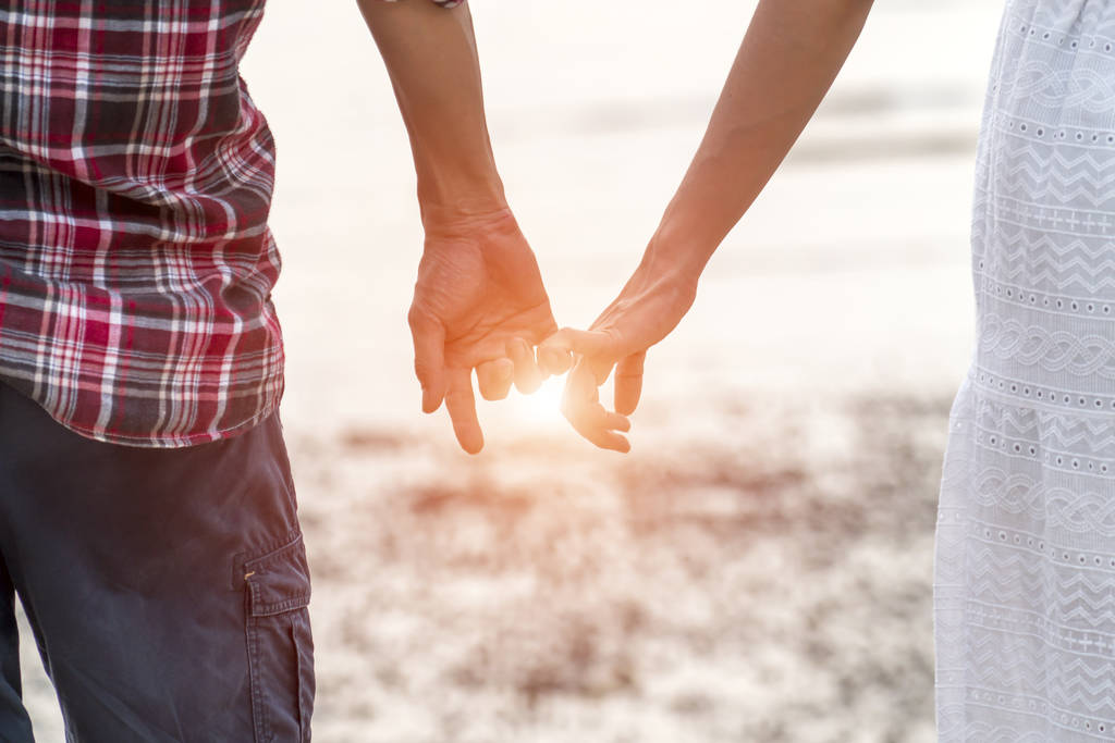 Пара держащихся за руки на пляже - Фото, изображение