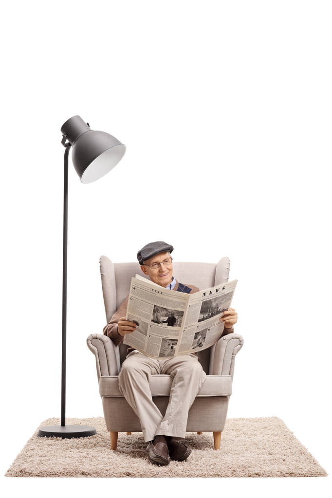 Ηλικιωμένος άνδρας διαβάζει μια εφημερίδα σε μια πολυθρόνα - Φωτογραφία, εικόνα