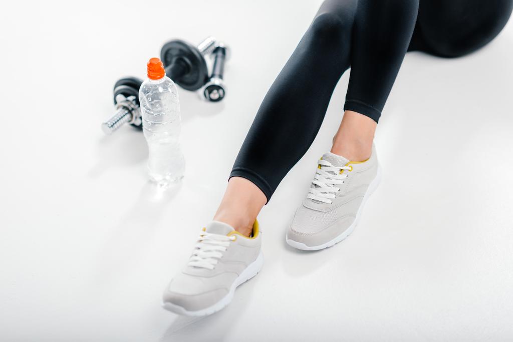 vrouw in sneakers met fitnessapparatuur - Foto, afbeelding