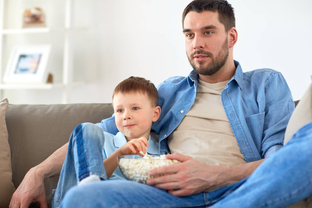 father and son with popcorn watching tv at home - Photo, Image