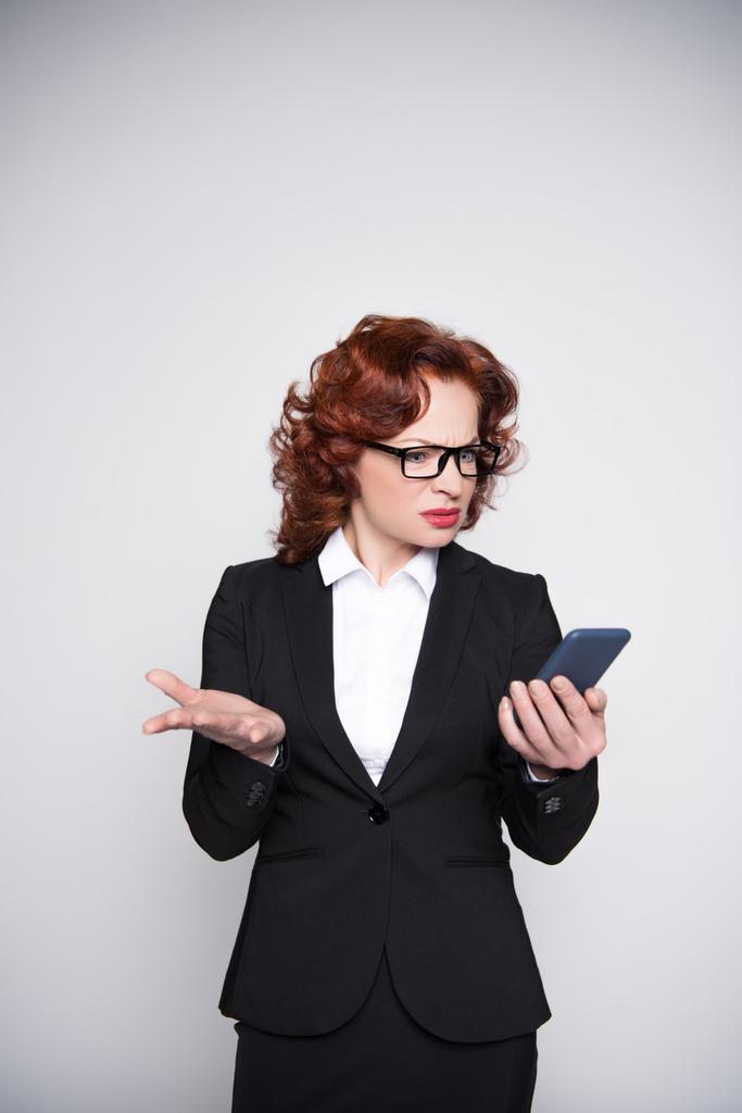Verwirrte Geschäftsfrau blickt aufs Smartphone - Foto, Bild
