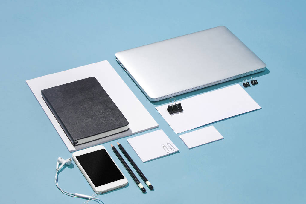 Kannettava tietokone, kynät, puhelin, muistilappu tyhjällä näytöllä pöydällä
 - Valokuva, kuva