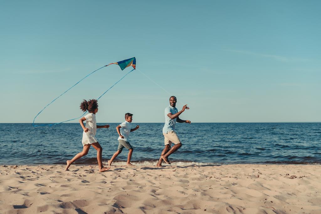 father and kids playing with kite on beach - Photo, Image