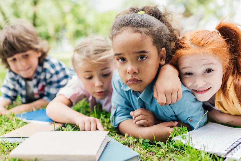 kinderen met boeken liggen op gras - Foto, afbeelding