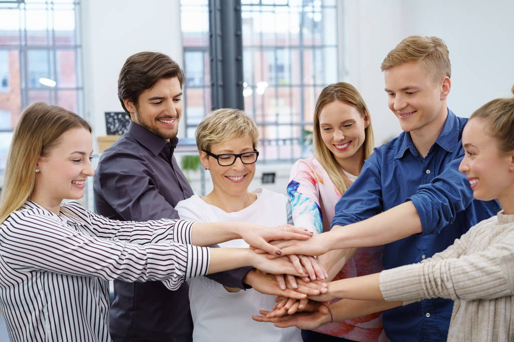 Six work colleagues participating in hands in team building exercise in office room - Photo, Image