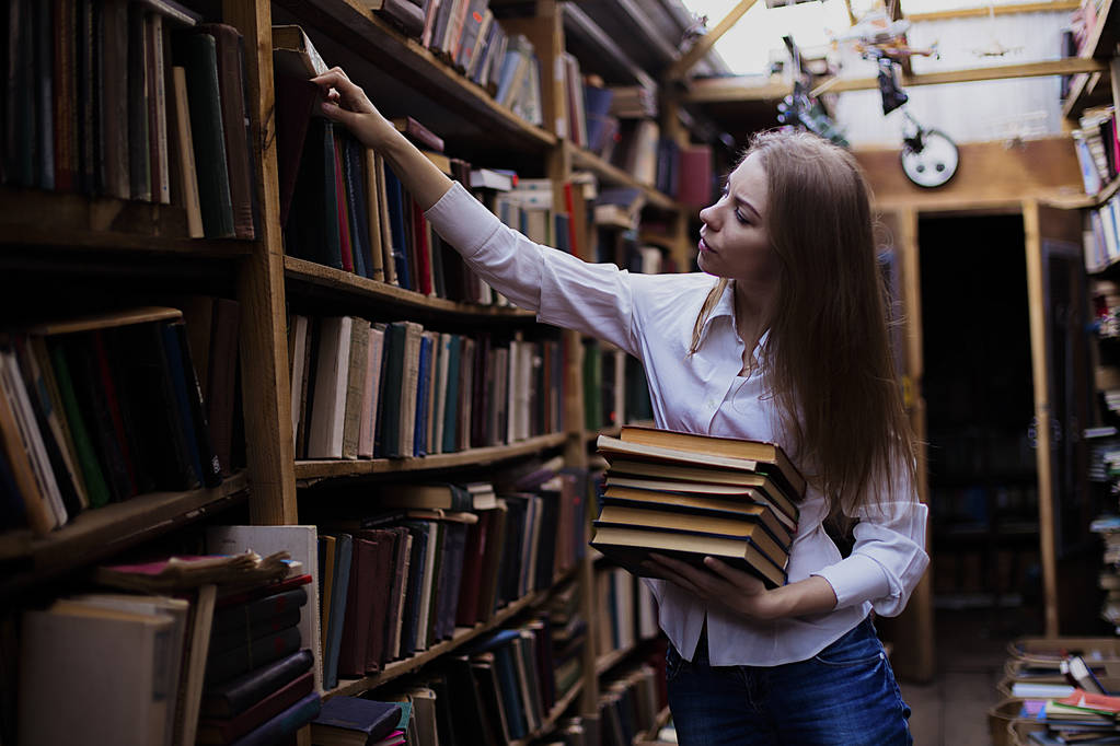 Lifestyle portrait of a lovely student girl in vintage library or bookstore - Photo, Image