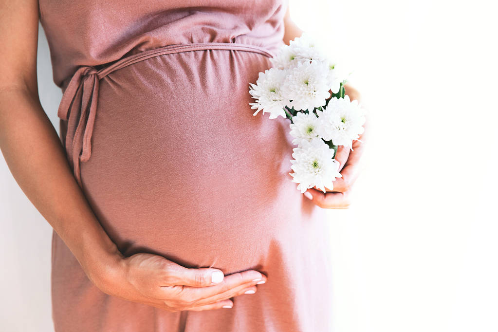 Close-up zwangere vrouw op een witte achtergrond.  - Foto, afbeelding