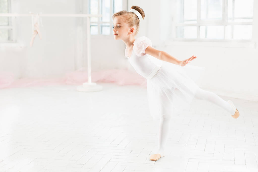 Pequeña bailarina en un tutú. Adorable ballet clásico de danza infantil en un estudio blanco
. - Foto, imagen