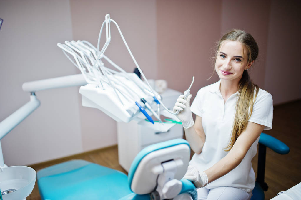 Hyvännäköinen naishammaslääkäri poseeraa joidenkin hammasinstrumenttien kanssa
  - Valokuva, kuva