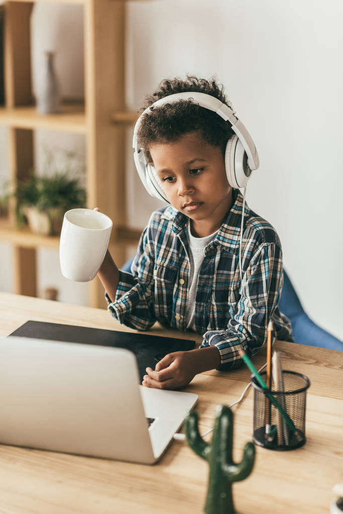 menino com fones de ouvido olhando para laptop
 - Foto, Imagem