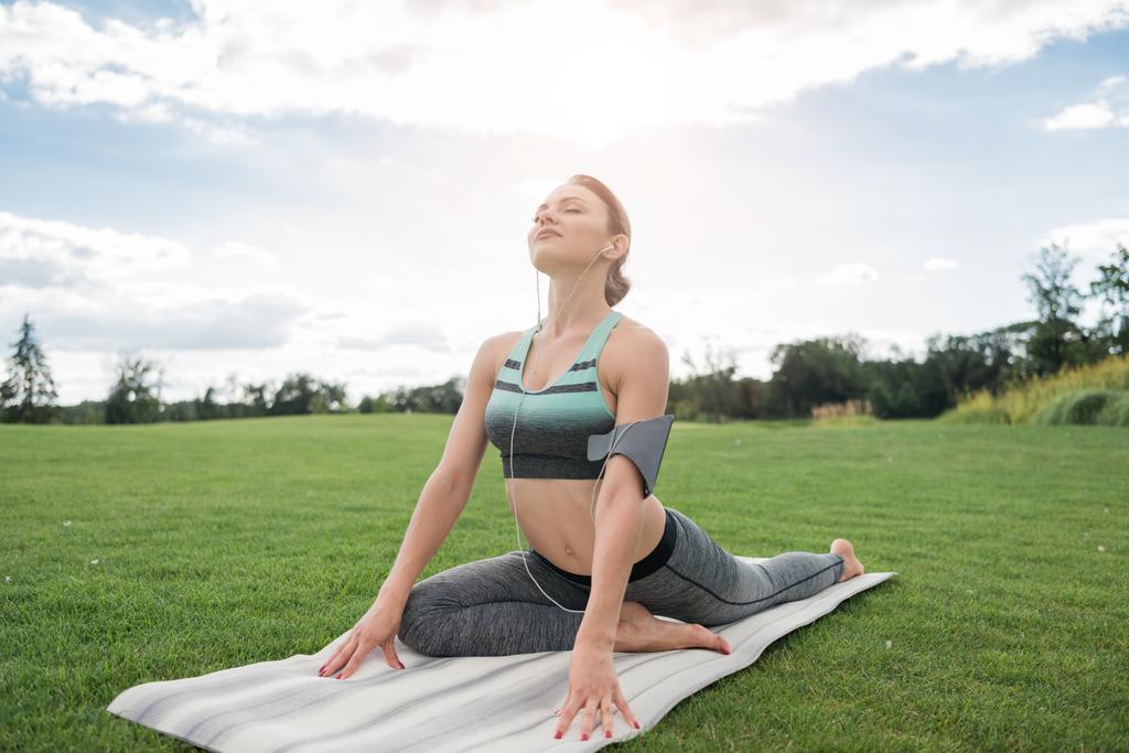 woman in earphones practicing yoga - Photo, Image