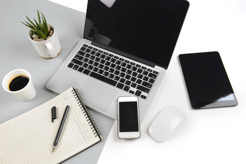 Office tabel met laptopcomputer, notebook, digitale tablet en smartphone op moderne tweetonige (wit en grijs) achtergrond. - Foto, afbeelding
