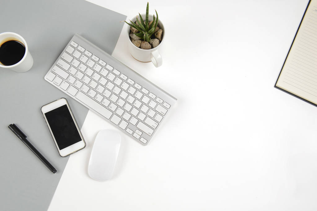 Office table with  keyboard, mouse, notebook and smartphone on modern two tone (white and grey) background. - Photo, Image