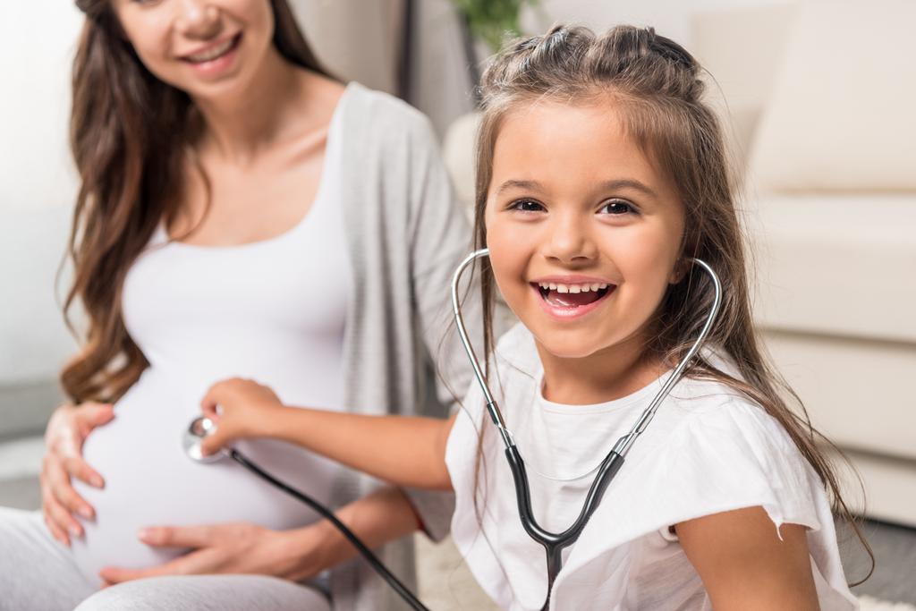 Ragazza ascoltando pancia incinta attraverso stetoscopio
 - Foto, immagini