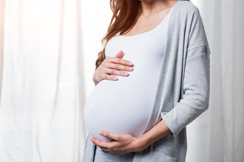 Zwangere vrouw raakt buik - Foto, afbeelding