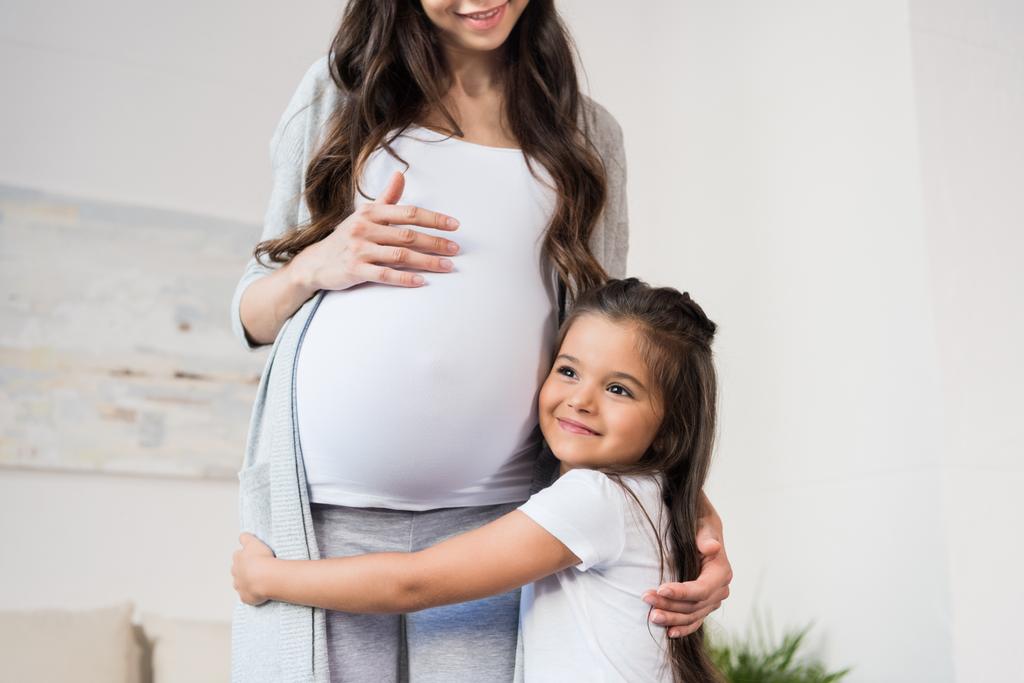 Knuffelen zwangere moeder van meisje - Foto, afbeelding
