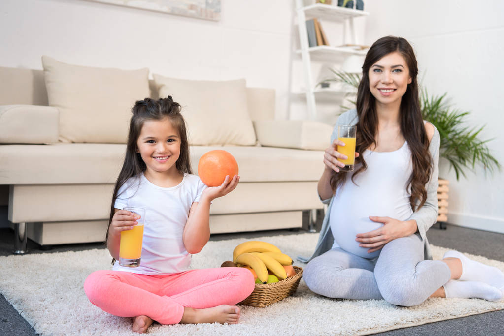 Mulher grávida e filha com copos de suco
 - Foto, Imagem