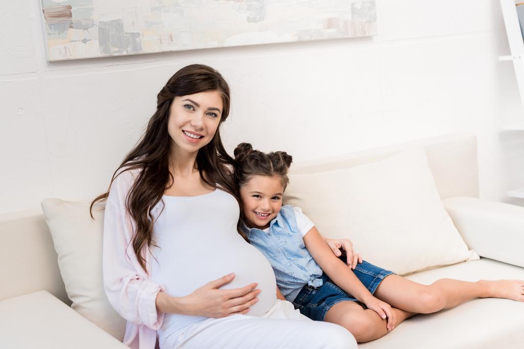 Ragazza e madre incinta che si abbraccia sul divano
 - Foto, immagini