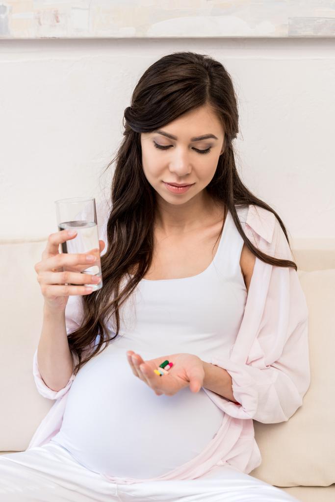 Mulher grávida segurando pílulas
 - Foto, Imagem