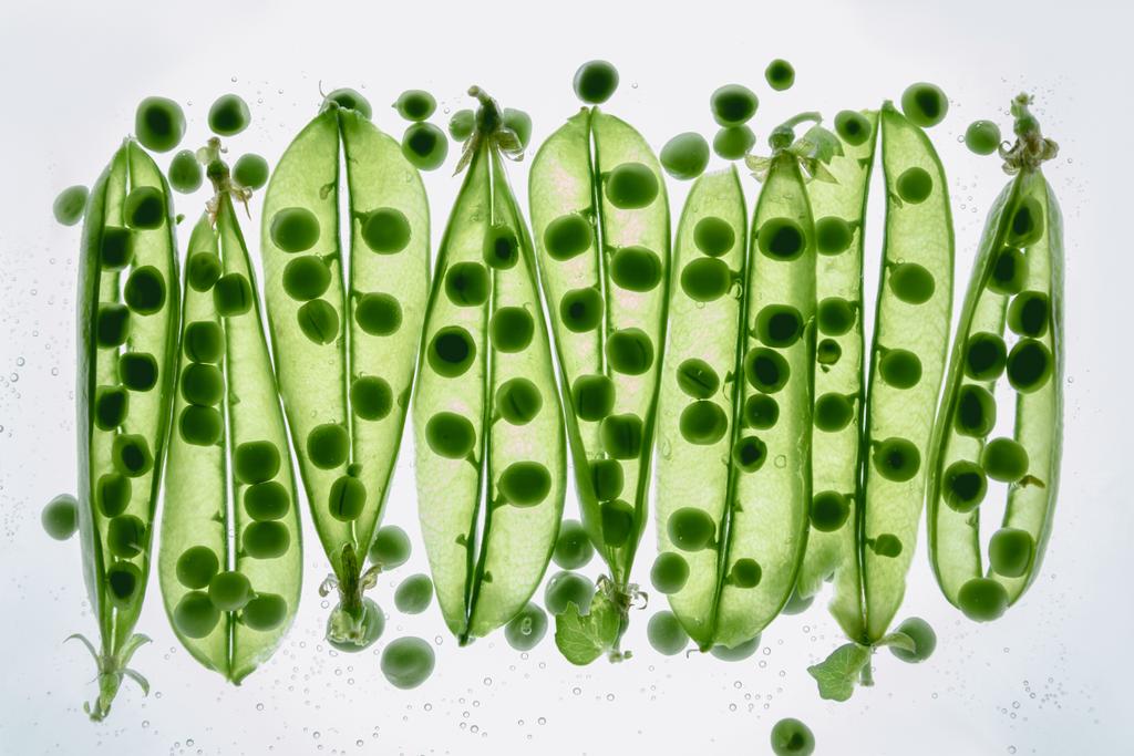 grüne Erbsen, die im Wasser treiben - Foto, Bild