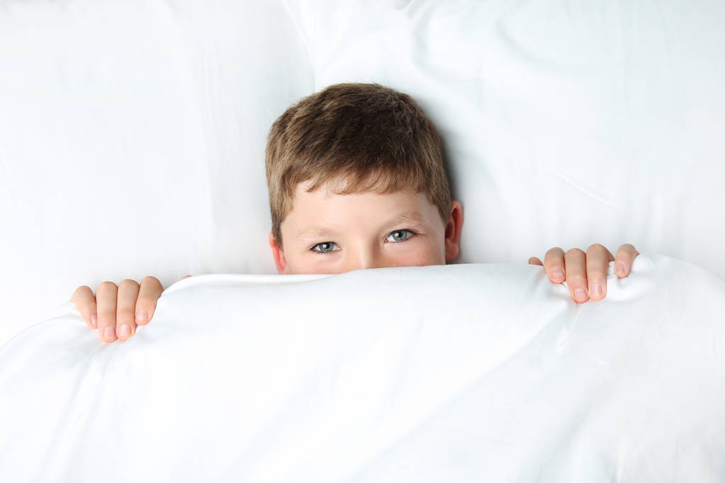Nuori poika nukkuu valkoisessa sängyssä
 - Valokuva, kuva