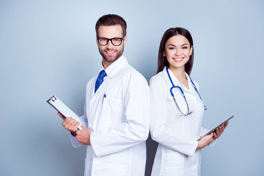Dos colegas médicos con batas blancas sobre fondo puro, sosteniendo
  - Foto, imagen