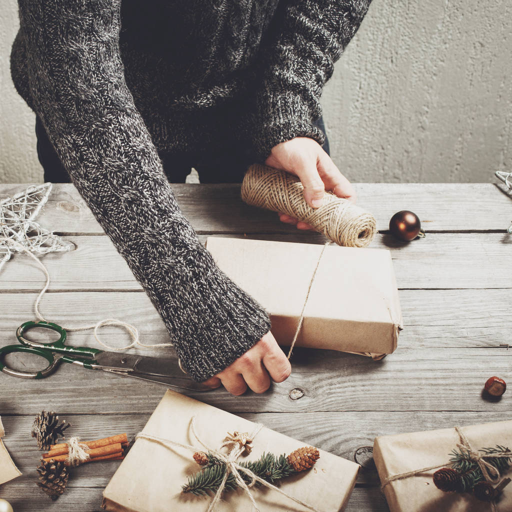 Αρσενικό χέρια τυλίξτε δώρο Χριστουγέννων στο ξύλινο τραπέζι - Φωτογραφία, εικόνα