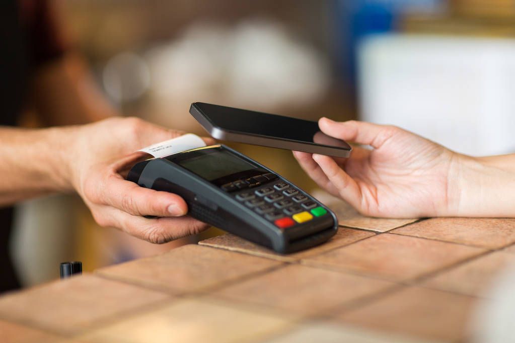 hands with payment terminal and smartphone at bar - Photo, Image