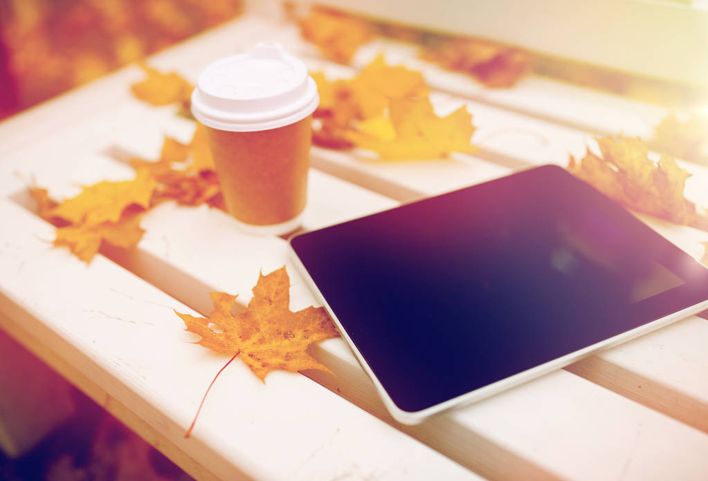 Tablet pc és a kávé-kupa őszi parkban a padon - Fotó, kép