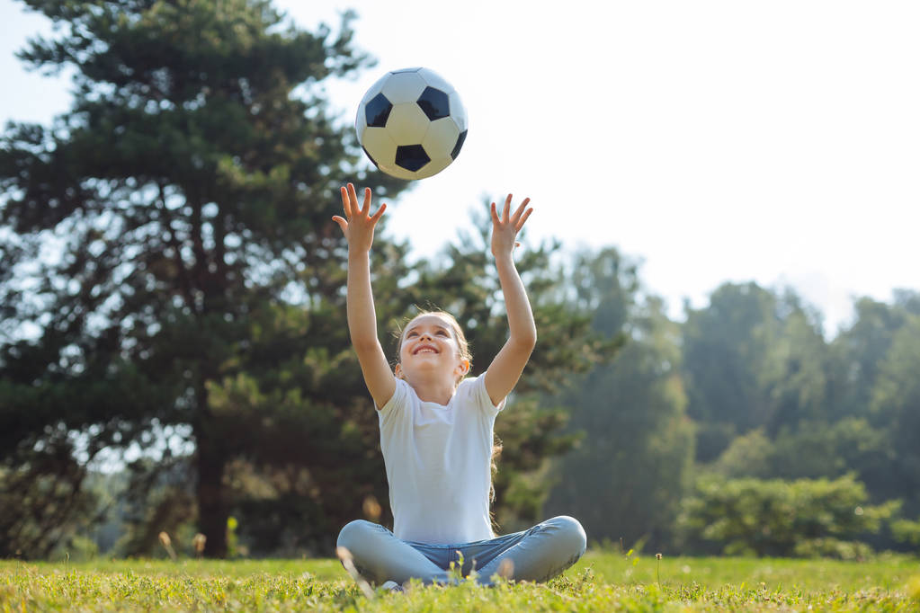 Αισιόδοξο κορίτσι ρίχνει μια μπάλα στον αέρα - Φωτογραφία, εικόνα