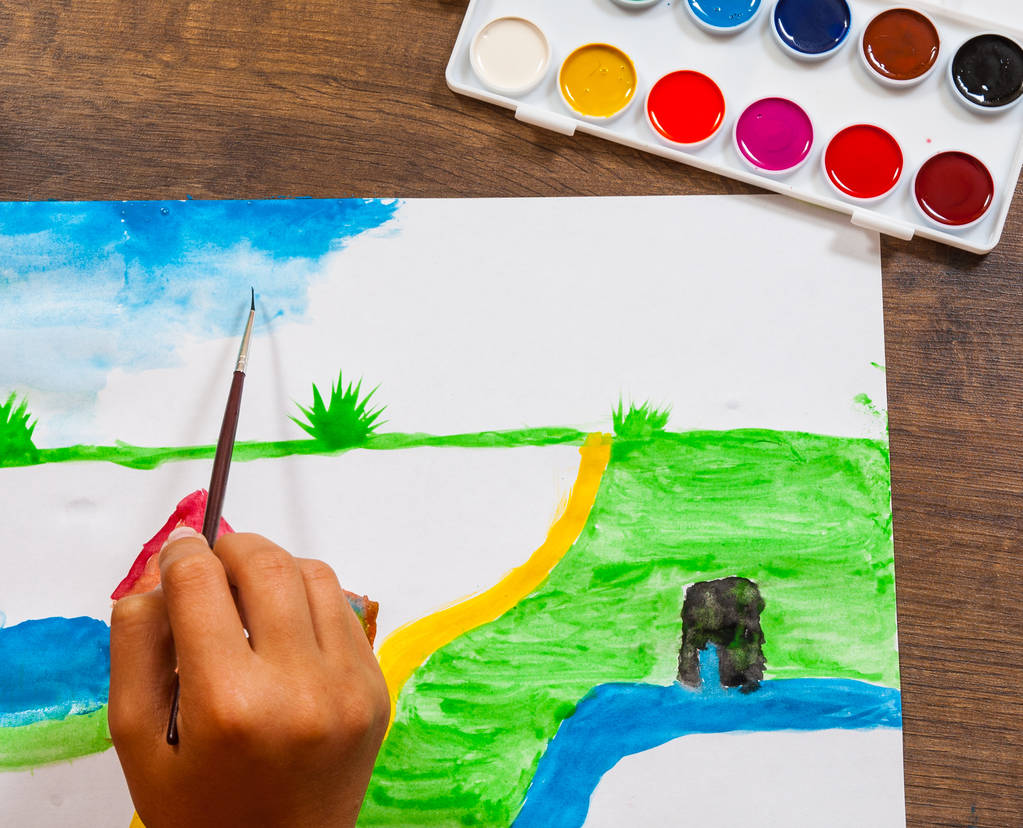 Рука ребенка рисует картину акварелью. вид сверху
 - Фото, изображение