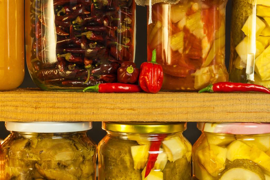 Jars with marinated food and organic raw vegetables. Preserved vegetables on wooden background. Various marinaded food. Life on a rural farm. - Photo, Image