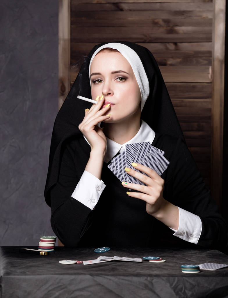 pali piękny zakonnica katolicka i karty do gry. Zgniłe religii - Zdjęcie, obraz