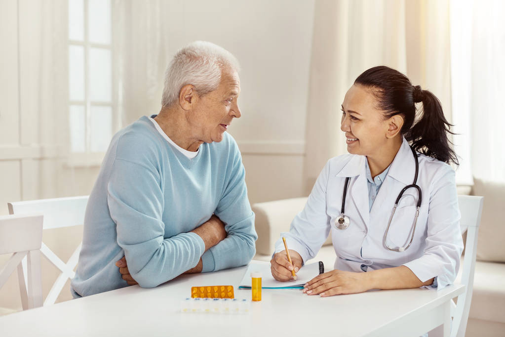 Delicioso médico alegre sentado junto con su paciente
 - Foto, Imagen