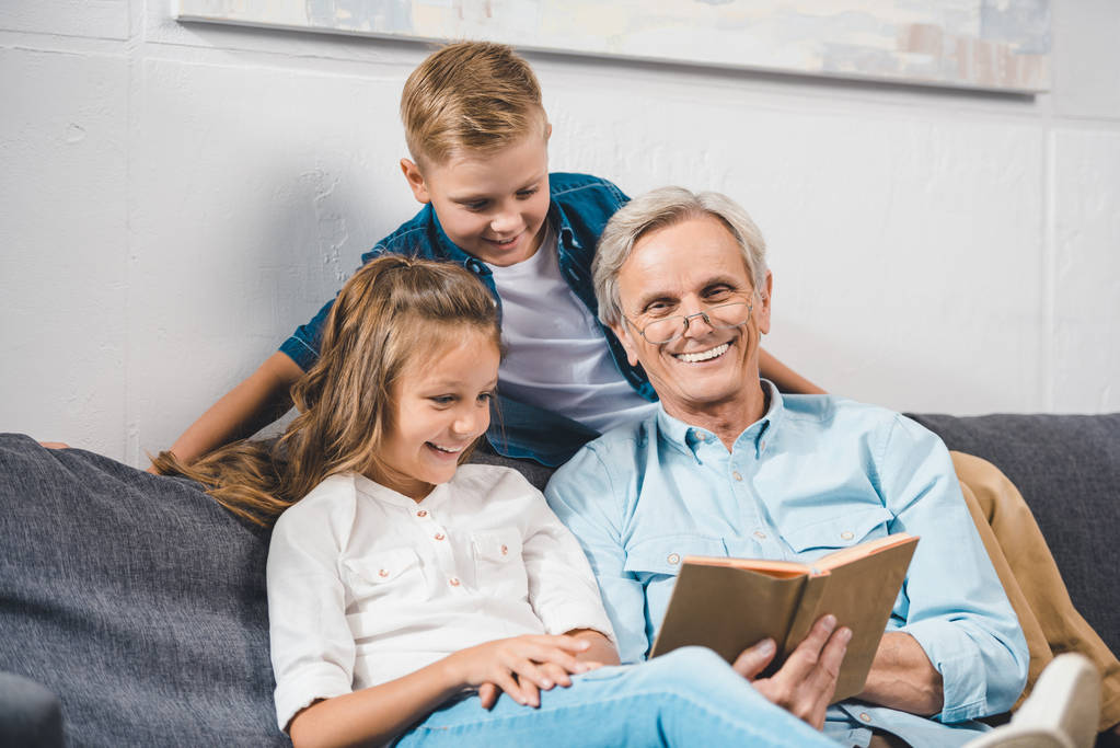 familia usando laptopabuelo y nietos leyendo libro
 - Foto, Imagen