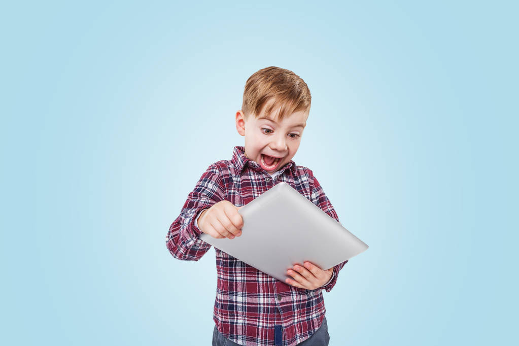 Portret van een enthousiast lachende jongen spelen tablet computer app - Foto, afbeelding