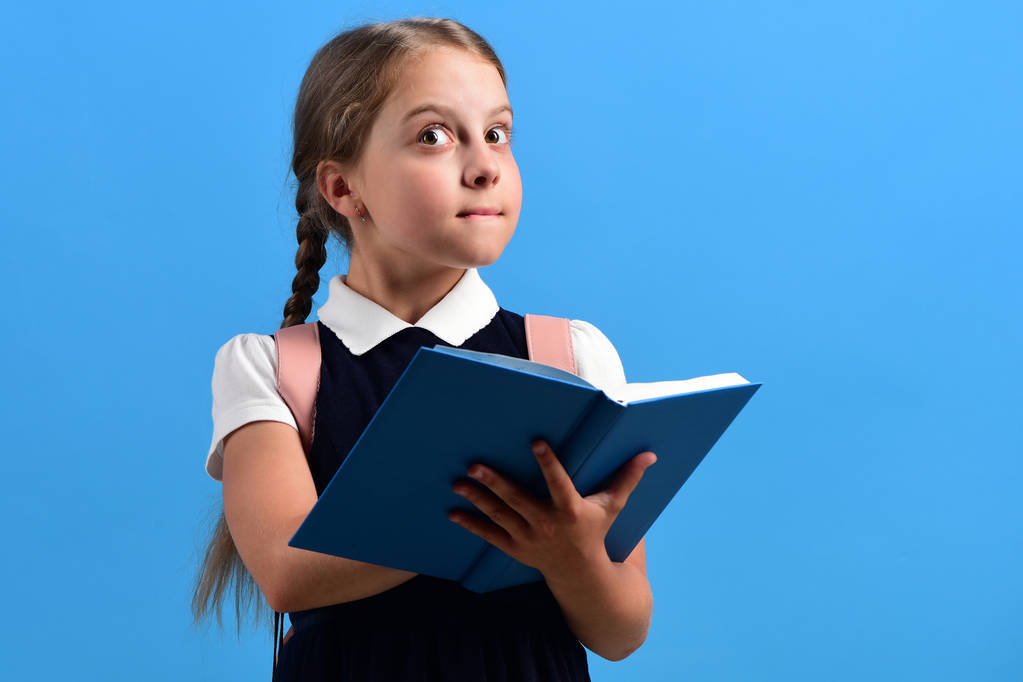 Okula ve eğitim konseptine geri dönmek. Kız mavi kitabı tutuyor. - Fotoğraf, Görsel