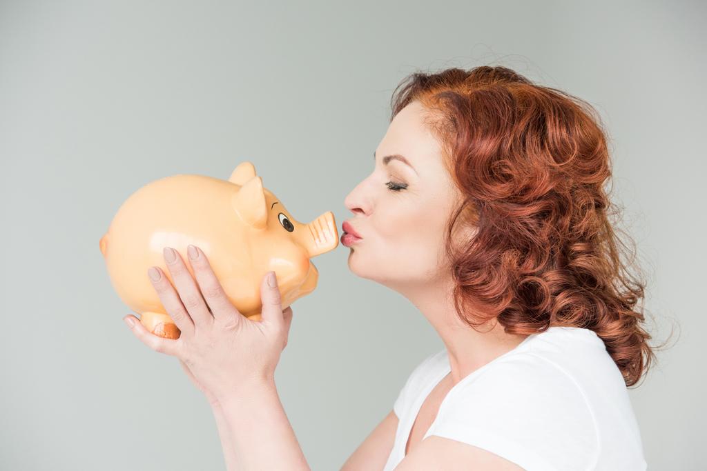vrouw zoenen piggy bank - Foto, afbeelding